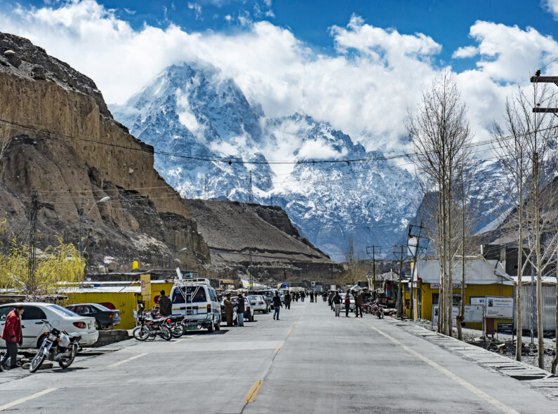 A wide road with people and cars on it, surrounded by mountains