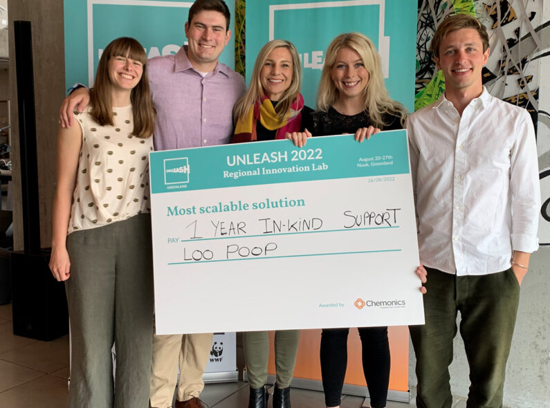 Five people posing for a photo with a large poster similar to a check that reads "UNLEASH 2022 Regional Innovation Lab; Most Scalable solution; Pay 1 year in-kind support; Loo Poop."