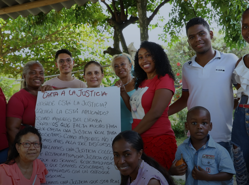 Group of people post with an oversized "letter to justice" written in Spanish