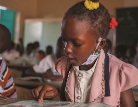 A young girl reading at her desk in a classroom