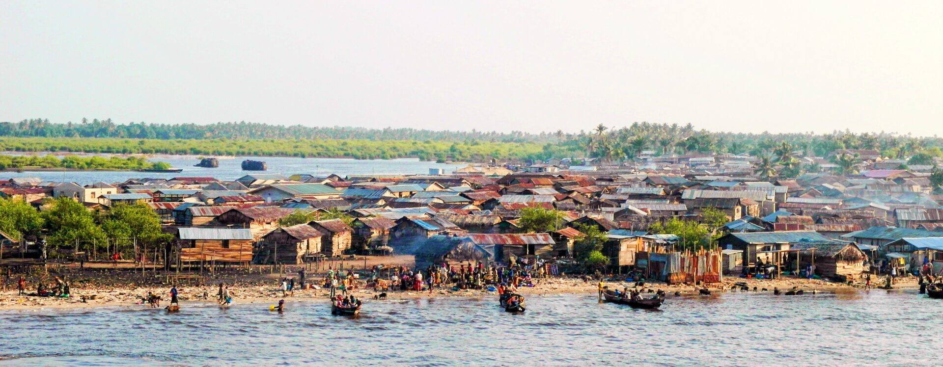 An image of a large town in Lagos beside a lagoon with several small ships in the water.