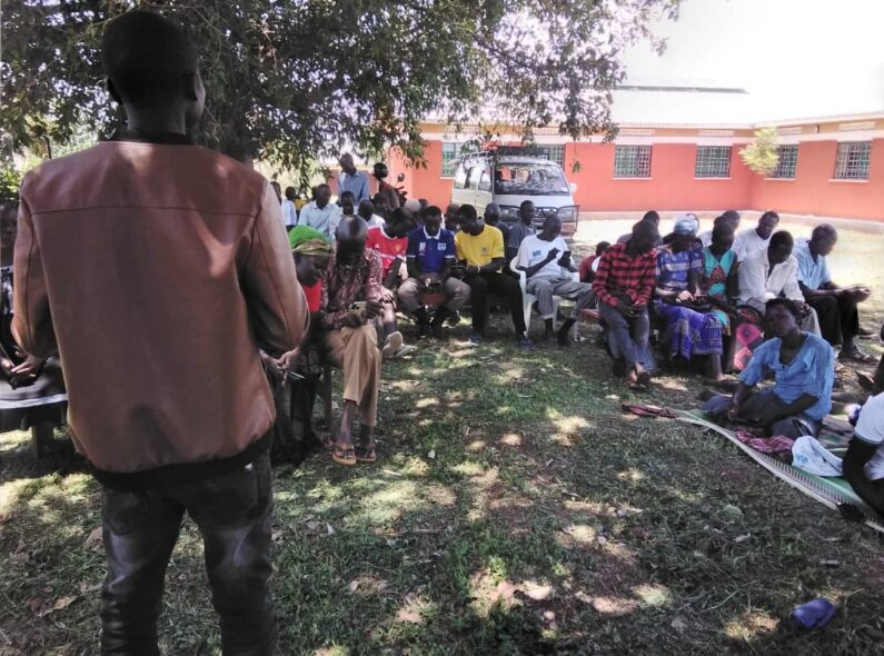 Village health team members meet outside in Uganda.