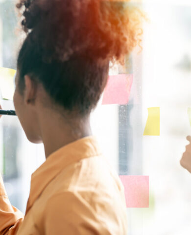 Stock image of people writing on Post-It notes in a learning session