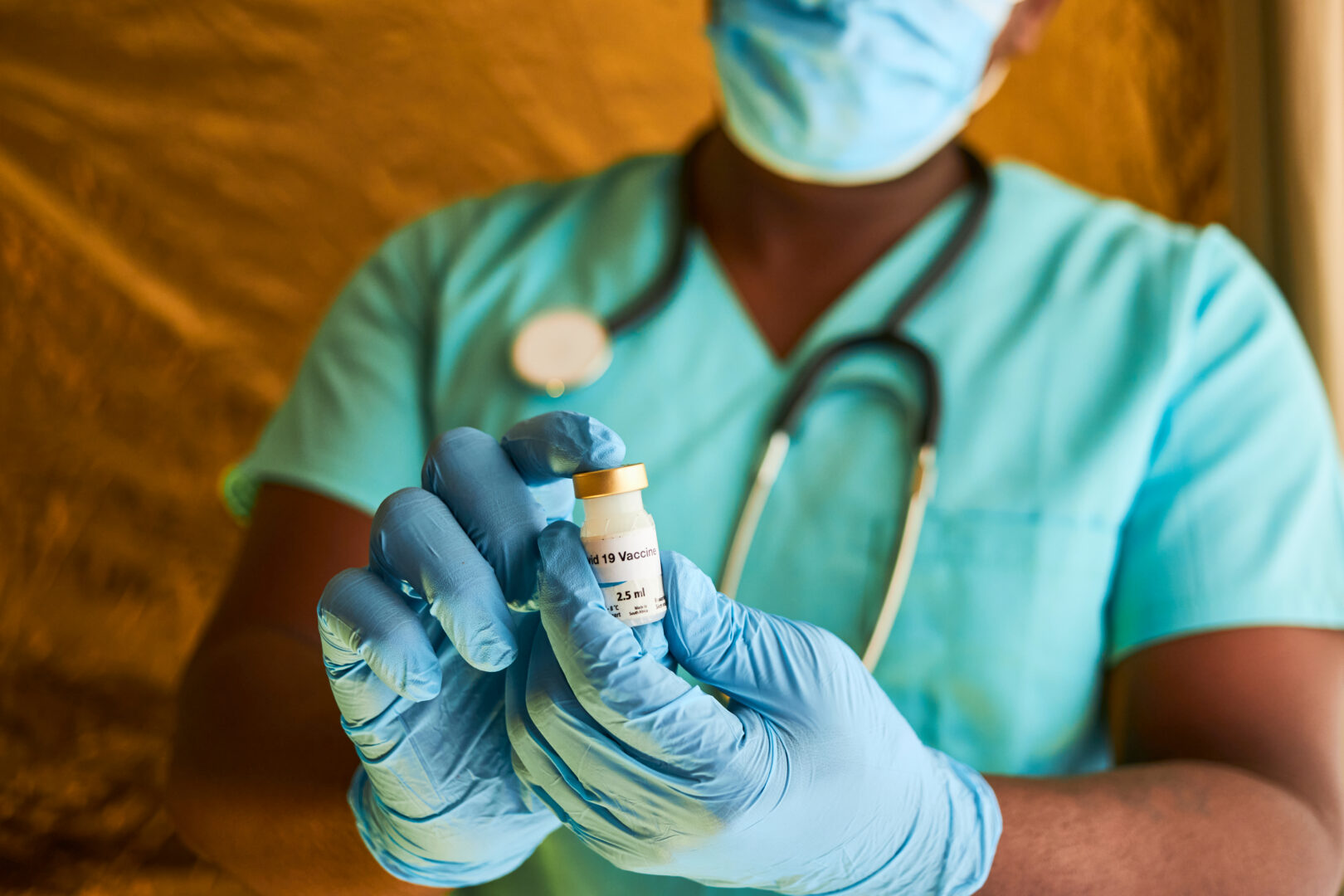 Person in scrubs holding medication with gloves on