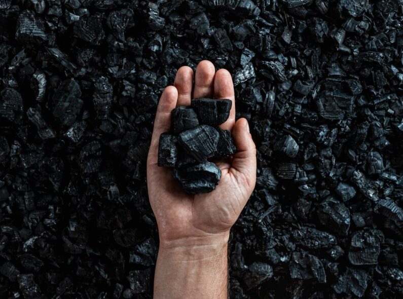 A background of coal, with a hand holding more coal set against it.