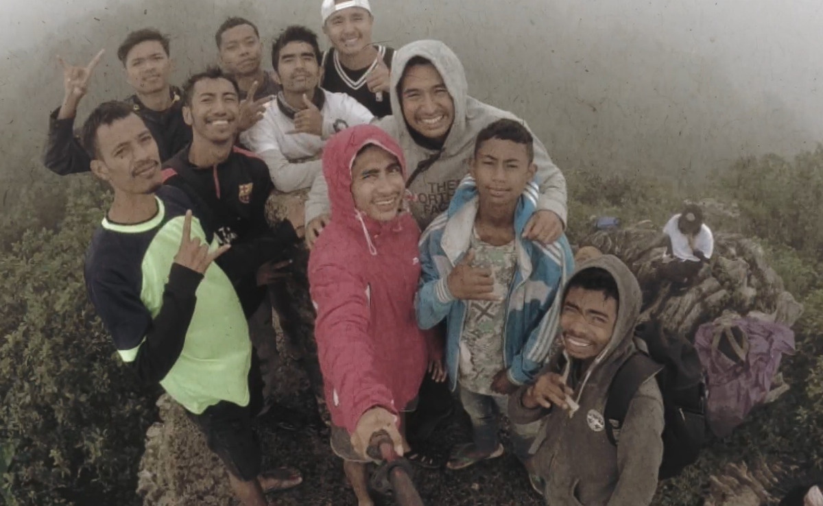 A group of young hikers take a selfie on top of a mountain