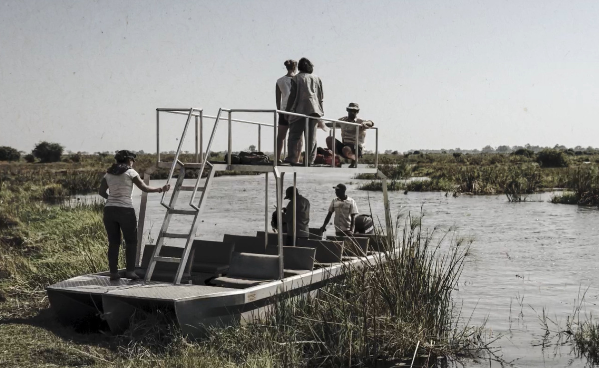 A group of young people prepare to launch a boat into a river.