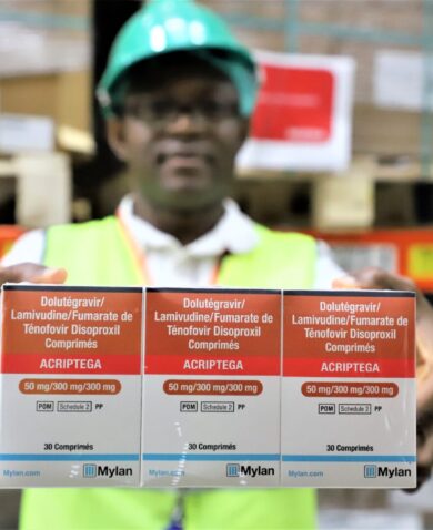 A warehouse worker in Nigeria holds boxes of TLD to the camera.