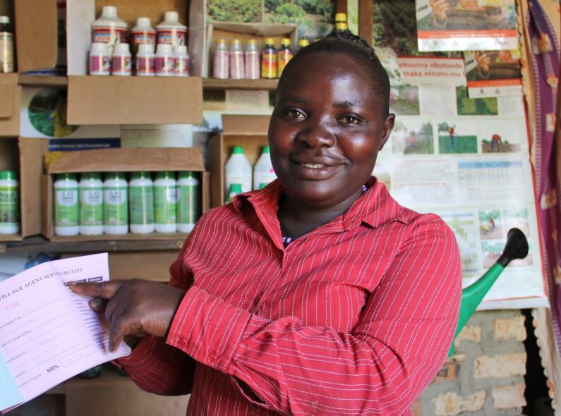A woman in Uganda shows a receipt for services rendered inside her small business.