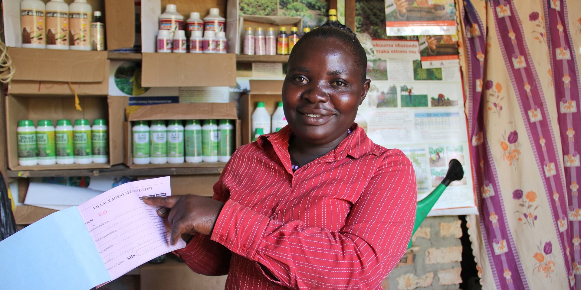 A woman in Uganda shows a receipt for services rendered inside her small business.