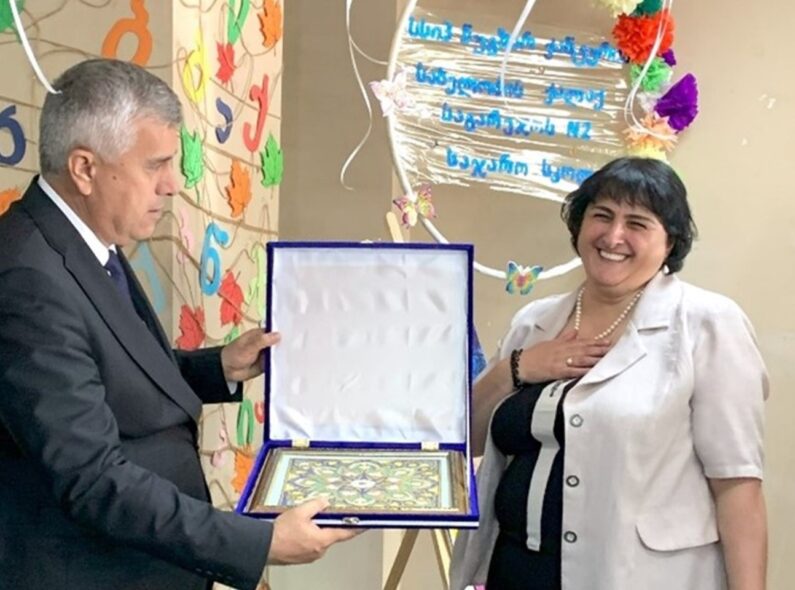 The Tajik Deputy Minister of Education and Science Abdulzoda presents a traditional Chakan embroidery to the principal of No. 2 Sagarejo Nugzar Chanturia Public School following a school visit.