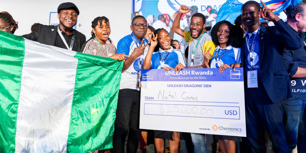 Many people celebrate with a Nigerian flag and giant check. Many pump their fists in the air.