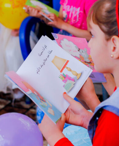A young female student with a book, taking part in a reading session with her classmates.