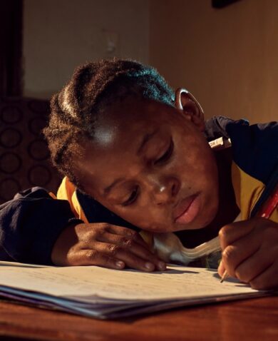 A young girl does her homework by candlelight