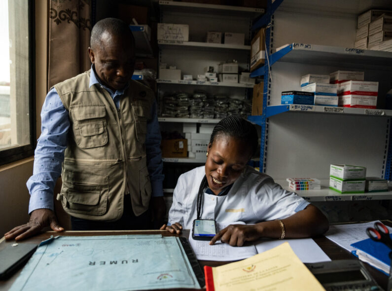 Two health workers at a facility in DRC use InfoMED to track stock level data of health commodities.