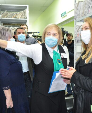 A group of people clad with masks stand in an office surrounded with files