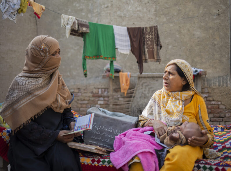 A lady health worker in patient consultation with a new mother.