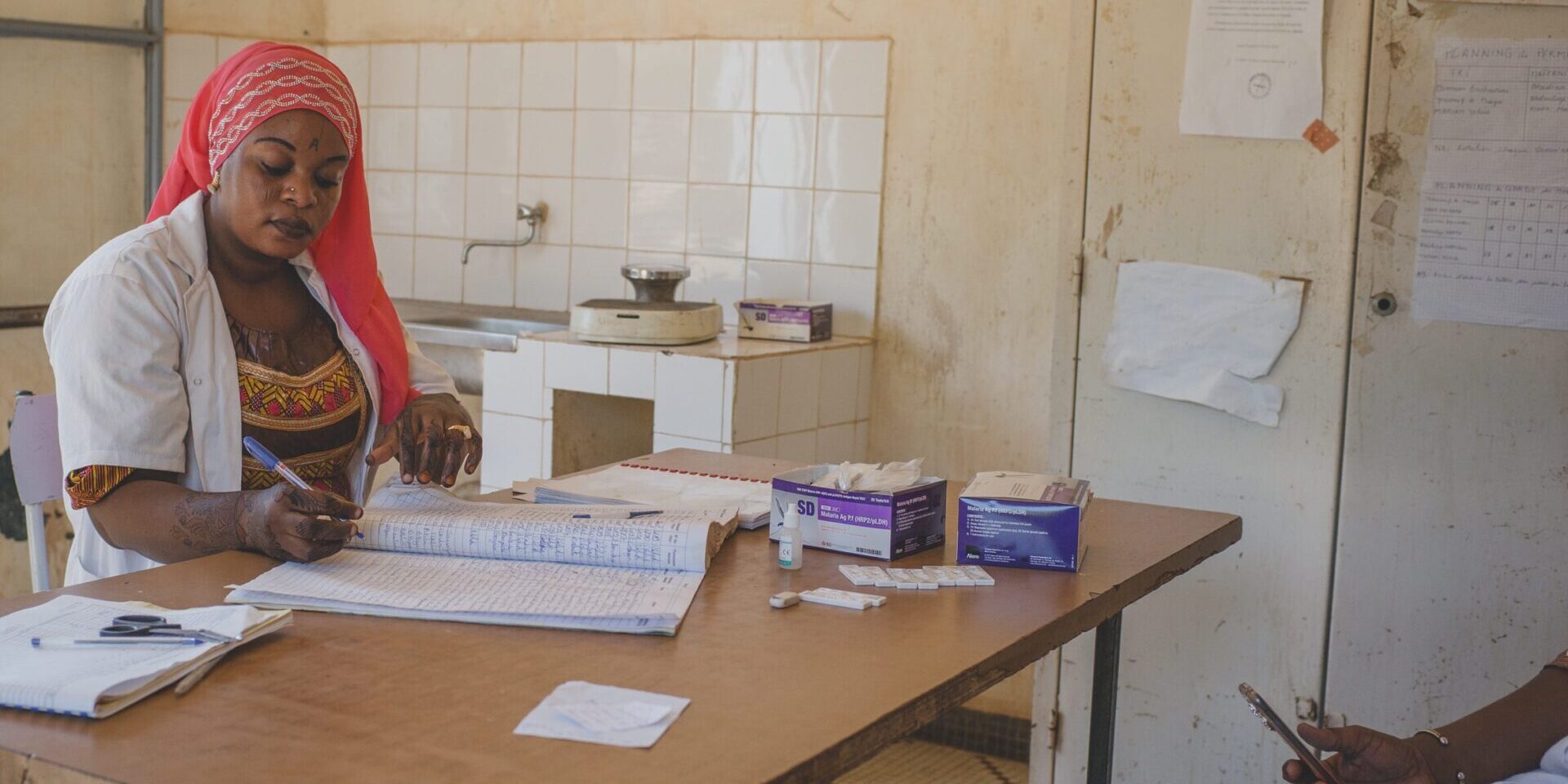 A female health worker sitting at a table, doing paperwork.