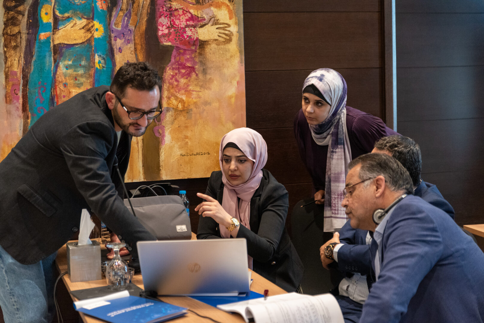 An instructor at a workshop (left) and a group of trainees stare at a computer.