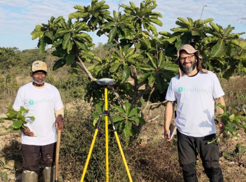 A forest steward and biologist stand in front of trees in Brazil