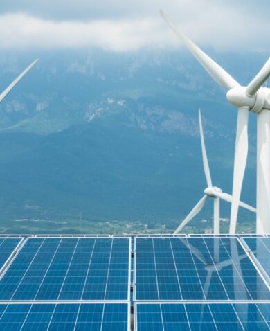 photo of solar panels and wind mills with mountains in the background