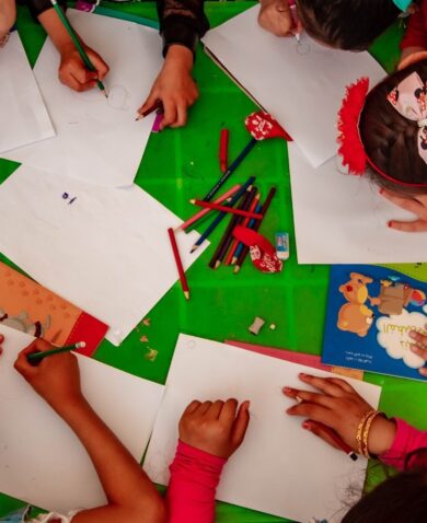 A group of children painting at a table, seen from above