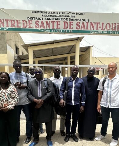 A group of 11 people stand in front of a sign that says "Health Center of Saint-Louis" in French.