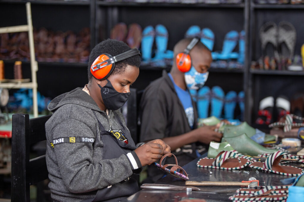 Two people in a workshop, handcrafting shoes.