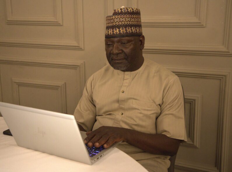 Pharmacist Patiko sits at a table, working on his laptop