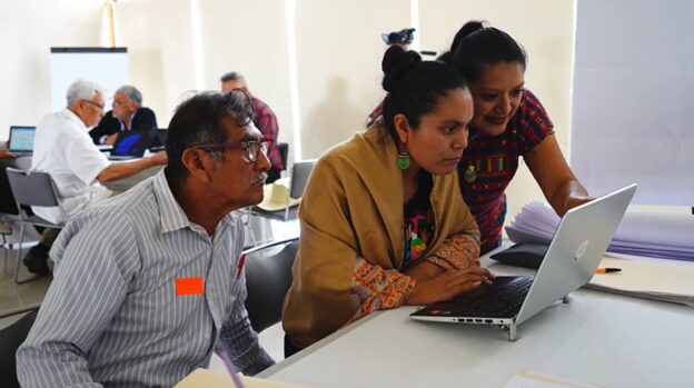 On woman shows two other people something on a laptop